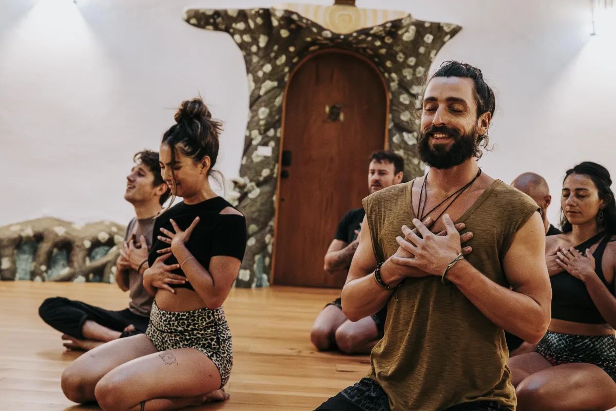 A group seated with their hands on their hearts, smiling with their eyes closed